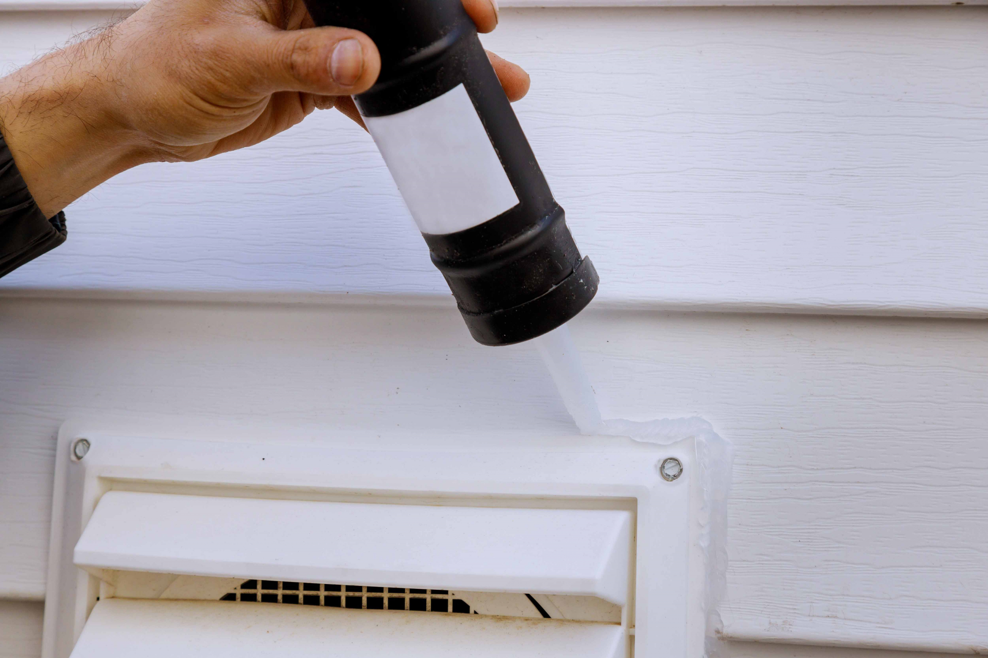 caulk being applied along a dryer vent cover